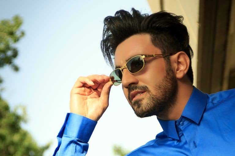 A man with dark hair and a long sleeve blue shirt modeling the best men's sunglasses for travel