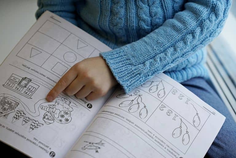 A child pointing at an activity in a workbook that fosters the smart travel for smart kids concept.